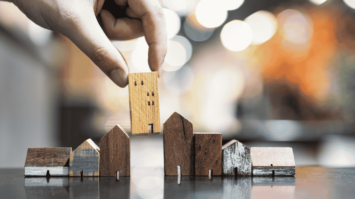 Hand placing a wooden building among miniature homes