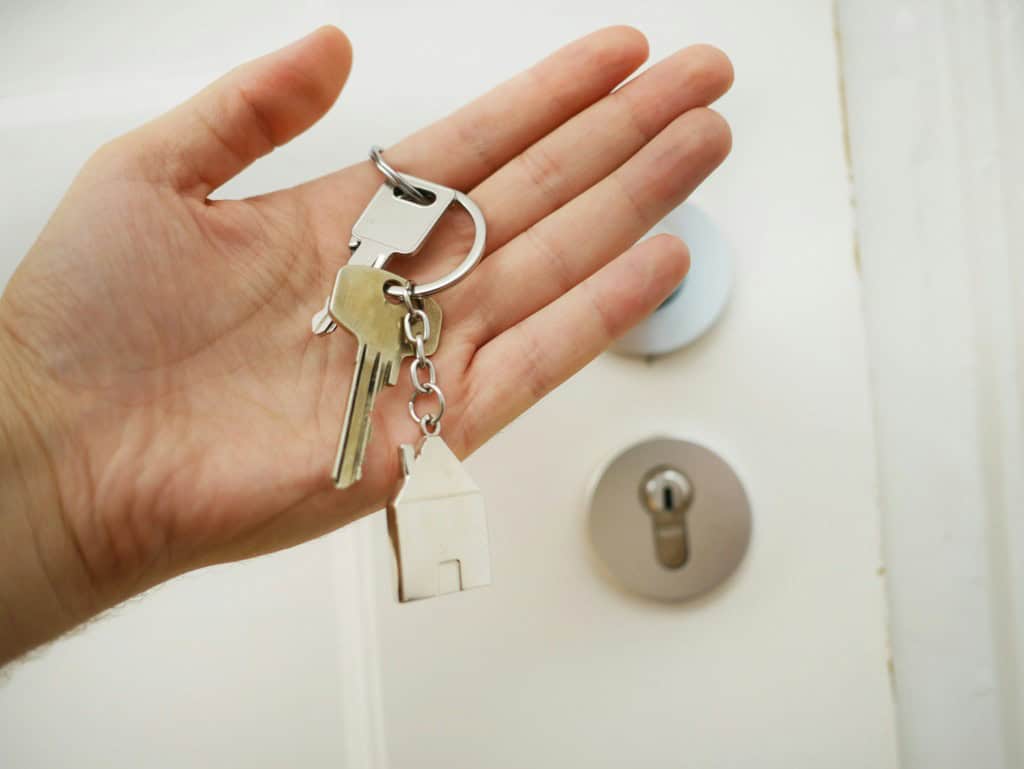 Hand holding house keys beside a residential door lock