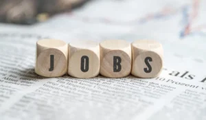 Wooden blocks spelling jobs on a newspaper business section