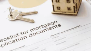 Mortgage application document checklist beside house keys and model home