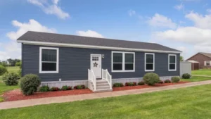 Single-story manufactured home with dark siding, white trim, and landscaped yard